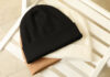 Three stylish beanies on wooden chair, top view