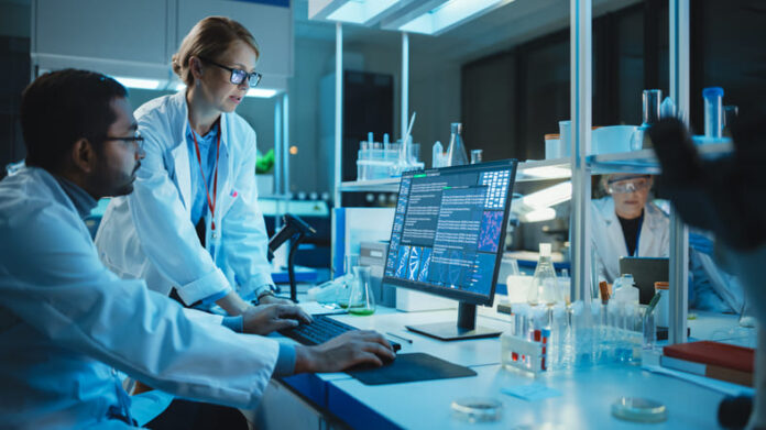 Female Research Scientist with Bioengineer Working on a Personal Computer with Screen Showing Gene Analysis Software User Interface.