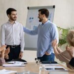 Young Caucasian businessman introduce new male employee or worker at group meeting in office.