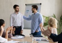 Young Caucasian businessman introduce new male employee or worker at group meeting in office.