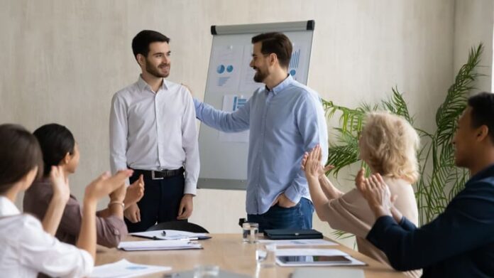 Young Caucasian businessman introduce new male employee or worker at group meeting in office.