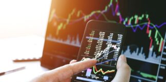 Businessman hand holding phone and analysis finance market graph stock market trading