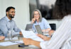 Senior female ceo and happy multicultural business people discussing company presentation at boardroom table.