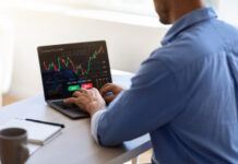 businessman working on laptop, sitting at desk in office, typing on keyboard, trading online, buying or selling bitcoins, cryptocurrency,