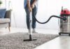 Woman cleaning rug carpet with vacuum cleaner