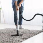 Woman cleaning rug carpet with vacuum cleaner