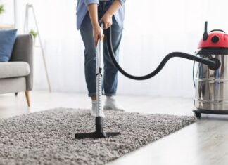 Woman cleaning rug carpet with vacuum cleaner