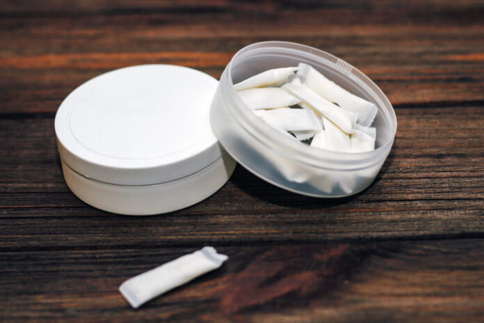 Snus box with nicotine pouches on wooden background