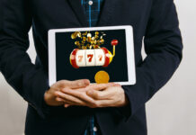 man in suit holding tablet with casino slot with jack pot on screen