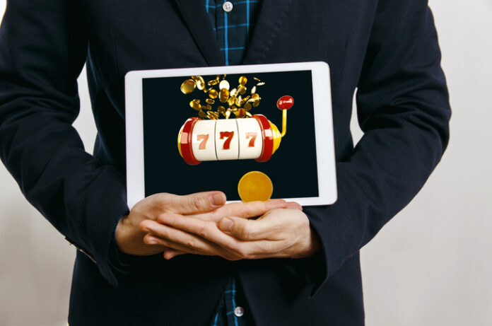 man in suit holding tablet with casino slot with jack pot on screen