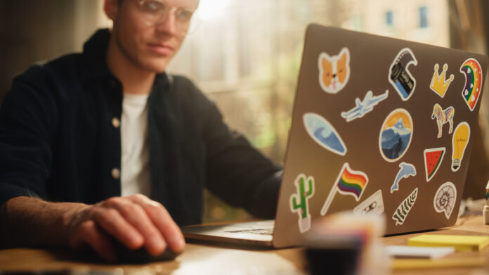 Man using laptop with stickers on the back