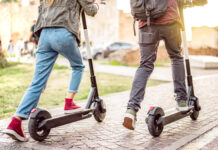 Couple riding electric scooters at urban city park