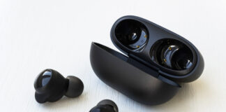 Wireless black earphones with contactless charging close-up on a white background.