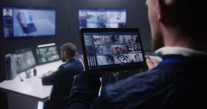 Close up shot of security officer zooming CCTV cameras with AI facial scanning