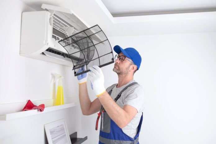 Service guy cleaning and maintaining air condition unit.