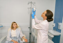 Professional doctor putting an IV drip to female patient intravenously in hospital ward