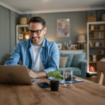 One man adult caucasian work on laptop at home happy smile