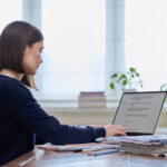 Young female using computer laptop for studying, working, serious young woman typing on keyboard.