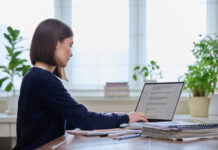 Young female using computer laptop for studying, working, serious young woman typing on keyboard.