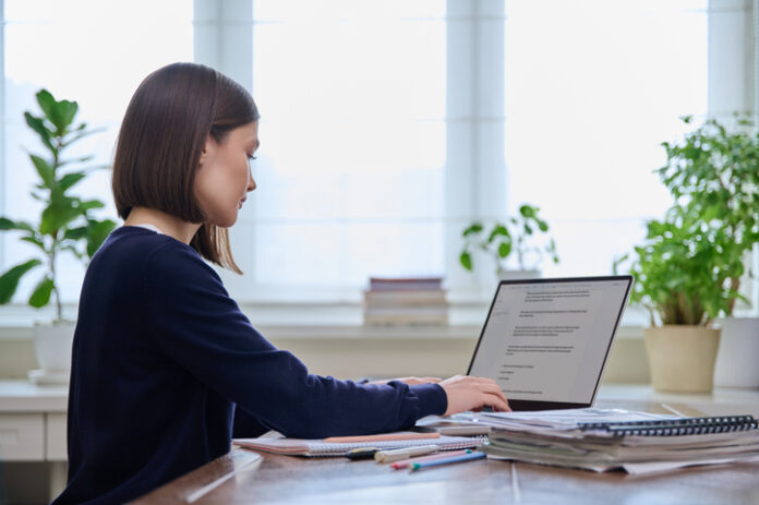 Young female using computer laptop for studying, working, serious young woman typing on keyboard.