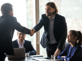 Smiling businessmen handshake closing successful deal at meeting