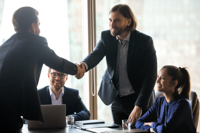 Smiling businessmen handshake closing successful deal at meeting