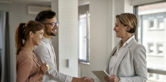 Happy couple greeting a real estate agent while buying a new home