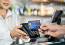 Close up shot of customer hand using dummy credit card for payment to waitress at cashier in cafe restauran