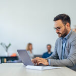 Serious-looking businessman using a modern technology, a laptop.