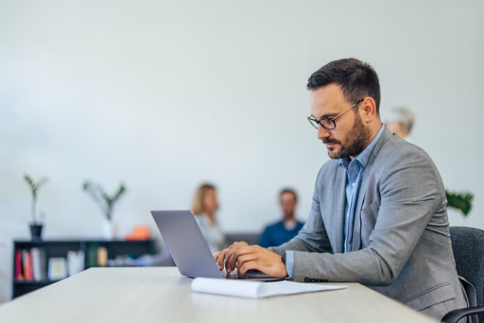 Serious-looking businessman using a modern technology, a laptop.