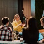 Businesswoman in wheelchair having business meeting with team at modern office.