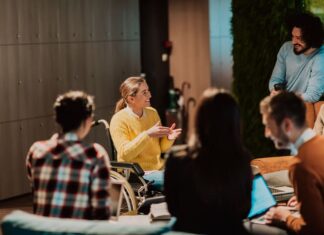 Businesswoman in wheelchair having business meeting with team at modern office.