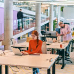 professional businesswoman with orange hair sitting at her laptop, epitomizing innovation and productivity in her contemporary workspace