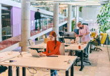 professional businesswoman with orange hair sitting at her laptop, epitomizing innovation and productivity in her contemporary workspace