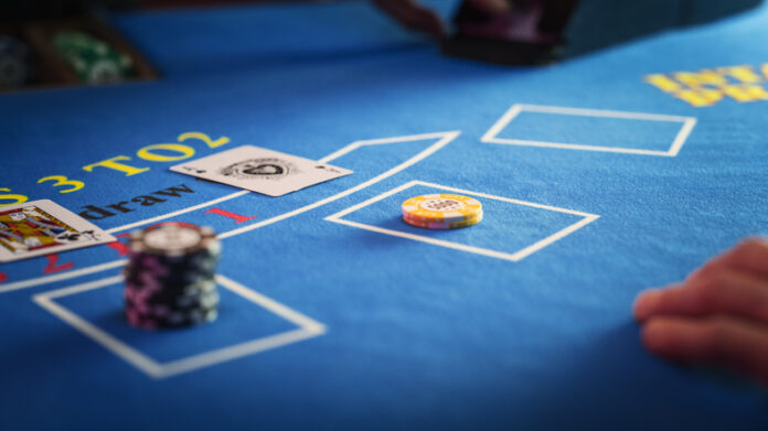 Anonymous Croupier Dealing Playing Cards on a Blackjack Table with Bet Chips in Place.