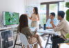 Asian woman lead young group of multiethnic businesspeople in team meeting, using laptop computer for ESG topic presentation on monitor.