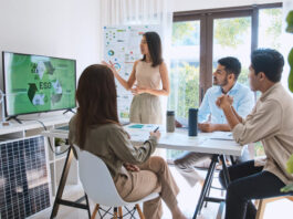 Asian woman lead young group of multiethnic businesspeople in team meeting, using laptop computer for ESG topic presentation on monitor.