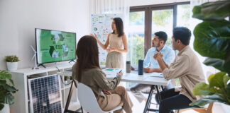 Asian woman lead young group of multiethnic businesspeople in team meeting, using laptop computer for ESG topic presentation on monitor.