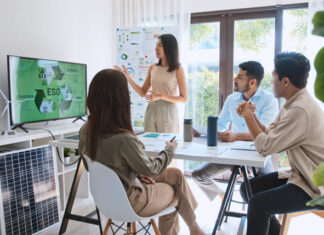 Asian woman lead young group of multiethnic businesspeople in team meeting, using laptop computer for ESG topic presentation on monitor.