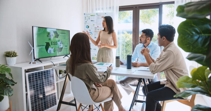 Asian woman lead young group of multiethnic businesspeople in team meeting, using laptop computer for ESG topic presentation on monitor.