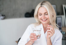 Middle age female holds pill and glass of water in her hands