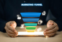 A person is holding a tablet with a marketing funnel on it