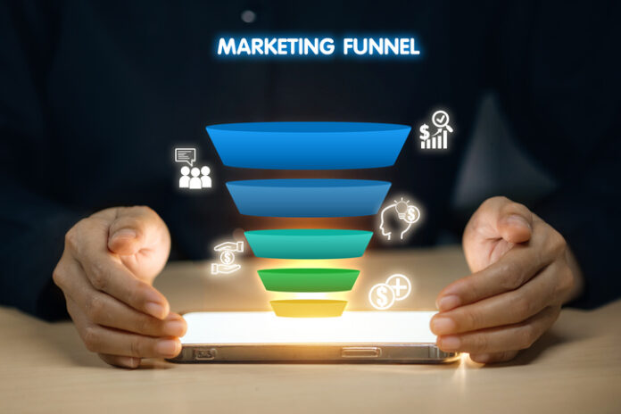 A person is holding a tablet with a marketing funnel on it