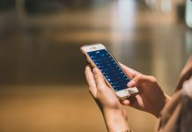 Close-up of hands holding a smartphone displaying a stock market app.