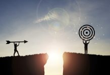 Silhouette men throwing arrow and holding dartboard on mountain with blue sky and sunlight for achievement objectives target