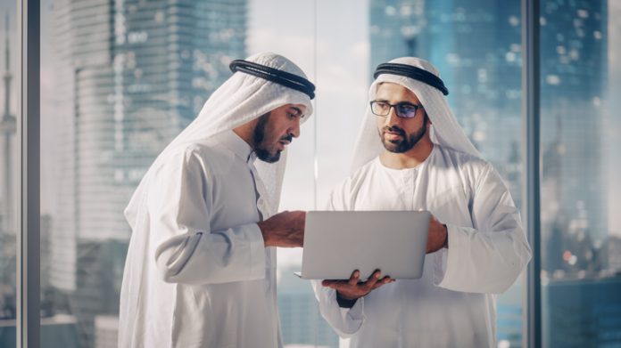 Two Successful Muslim Businessmen in White Traditional Outfit Standing in Office Meeting