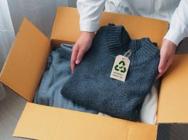 An environmentally conscious entrepreneur packs clothes made from natural materials into cardboard boxes to ship to customers