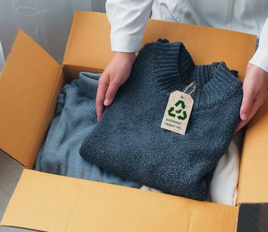 An environmentally conscious entrepreneur packs clothes made from natural materials into cardboard boxes to ship to customers