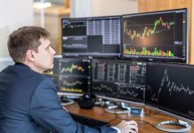 Stock trader looking at computer screens in trading office