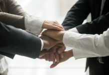 Diverse business team holding pile of hands promising loyalty